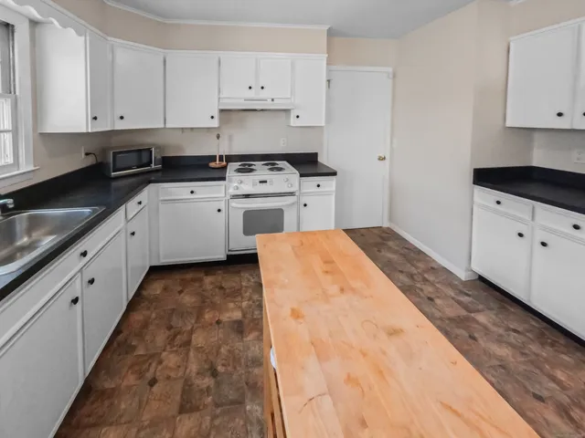 a kitchen with stainless steel appliances granite countertop a stove a sink and white cabinets