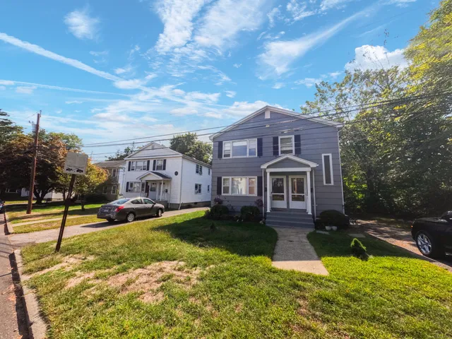 a view of a house with a big yard and large trees