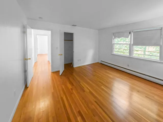 an empty room with wooden floor windows and exposed bricks