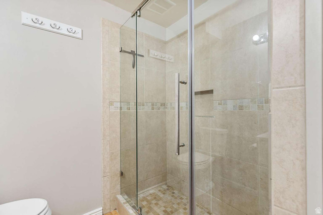 415 East 1150th Street North Logan, UT 84341 - Photo 29 of 38 Glass-enclosed shower featuring beige wall tiles, a decorative mosaic accent band, and a tile floor