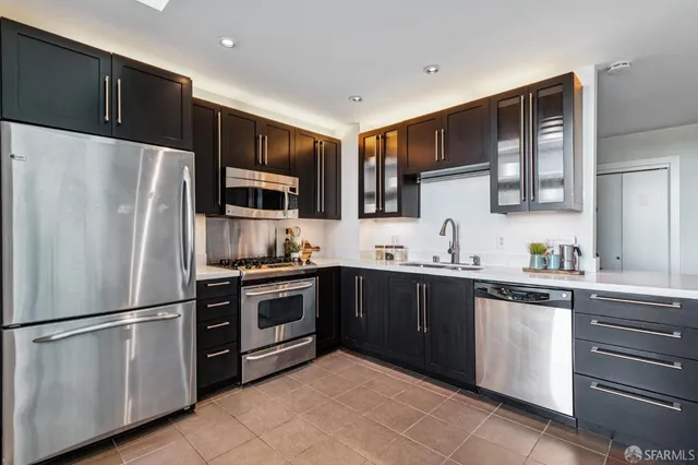 a kitchen with stainless steel appliances granite countertop a refrigerator stove a sink dishwasher and microwave