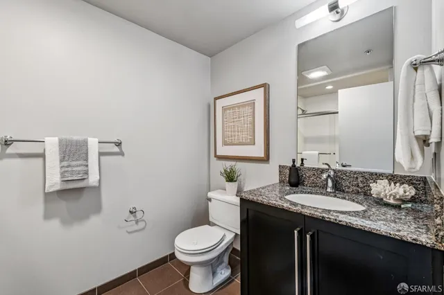 a bathroom with a granite countertop sink toilet and mirror