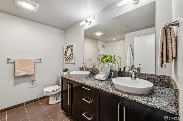 a bathroom with a granite countertop sink a toilet a mirror and vanity