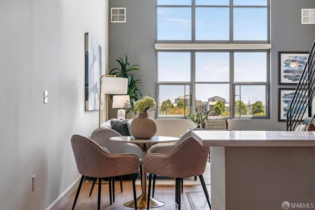 a dining room with furniture a potted plant and a floor to ceiling window