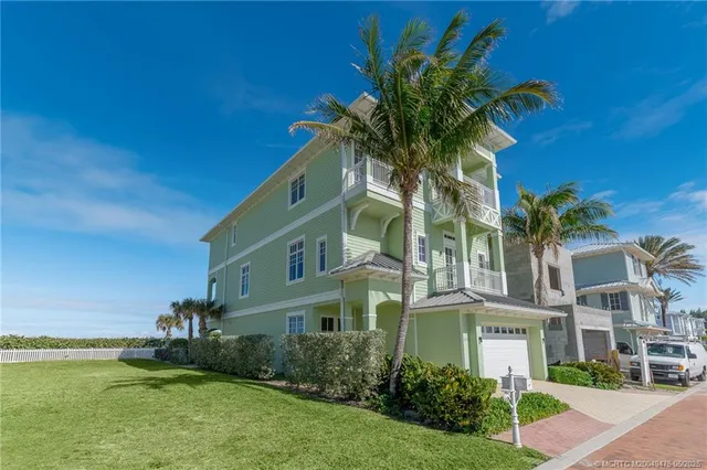 a living room with furniture two large window and a chandelier