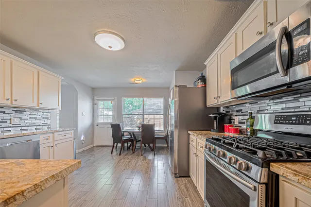 a kitchen with stainless steel appliances a stove a sink dishwasher and cabinets with wooden floor