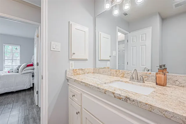 a en suite bathroom with a granite countertop sink and a mirror