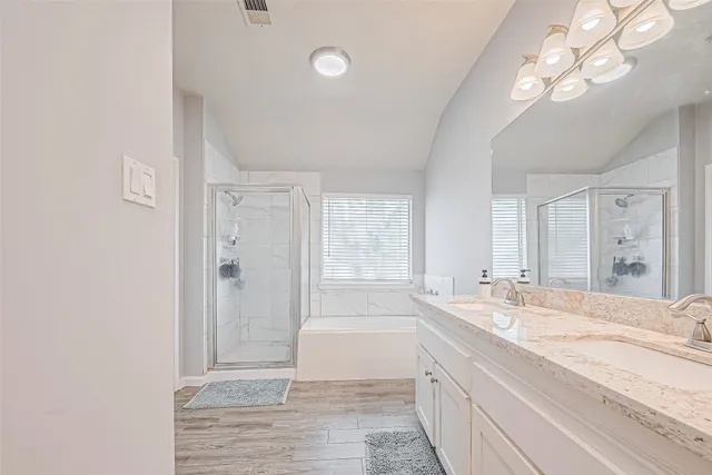 a spacious bathroom with a granite countertop sink a mirror and a bathtub