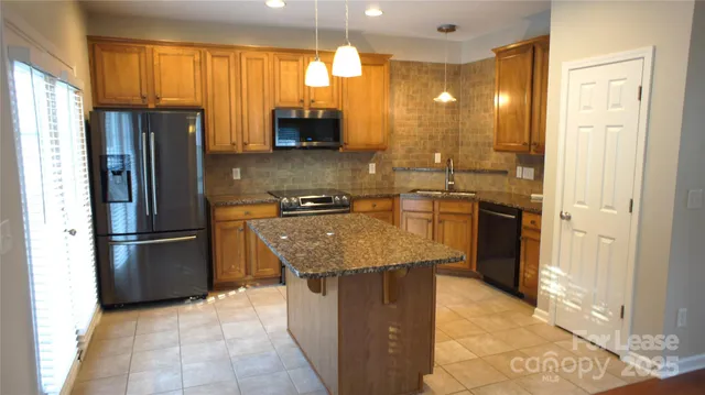 a kitchen with stainless steel appliances granite countertop a refrigerator a stove and a sink
