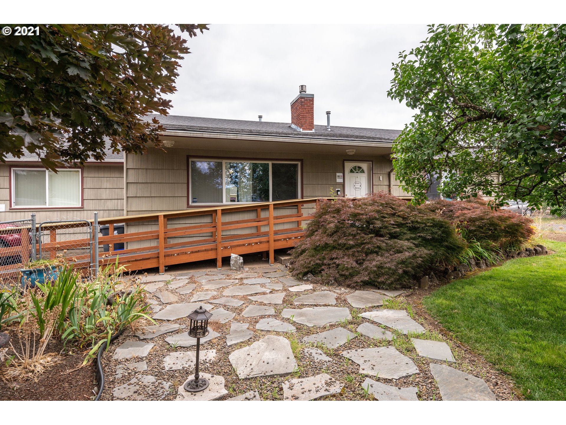 a view of backyard of house with wooden deck and outdoor seating