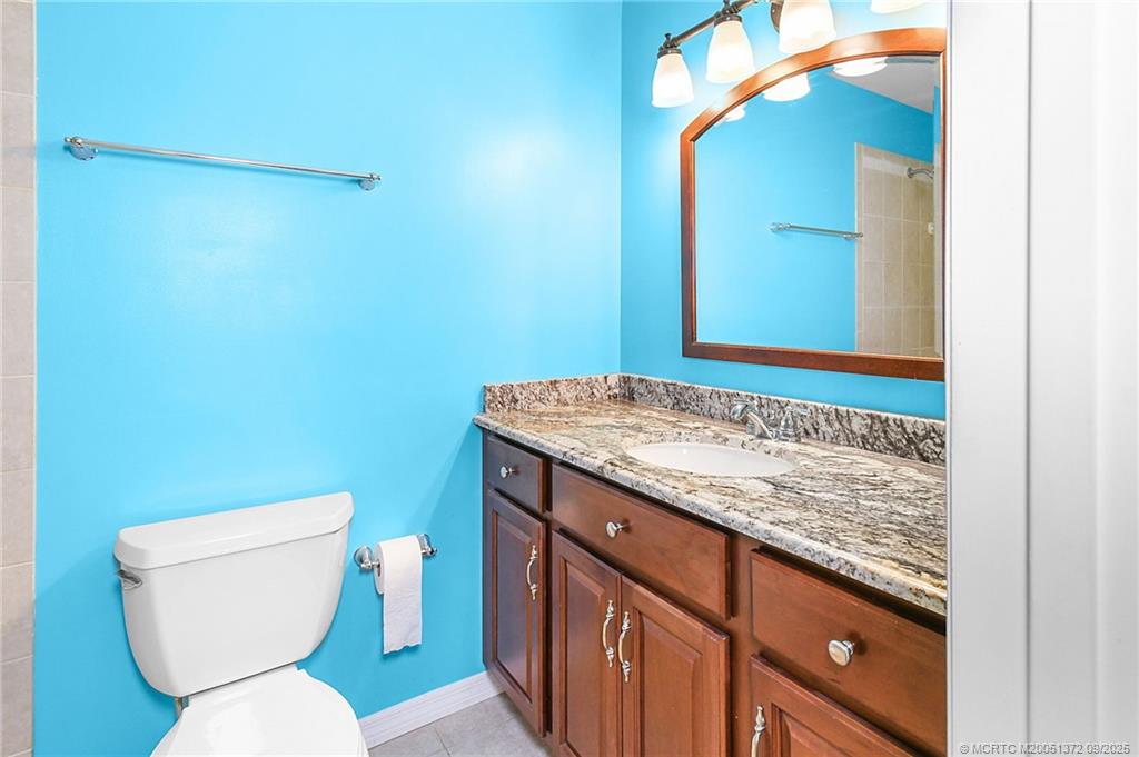 50 Southwest Blackburn Terrace, Unit 8 Stuart, FL 34997 - Photo 17 of 42 a bathroom with a granite countertop toilet sink and mirror