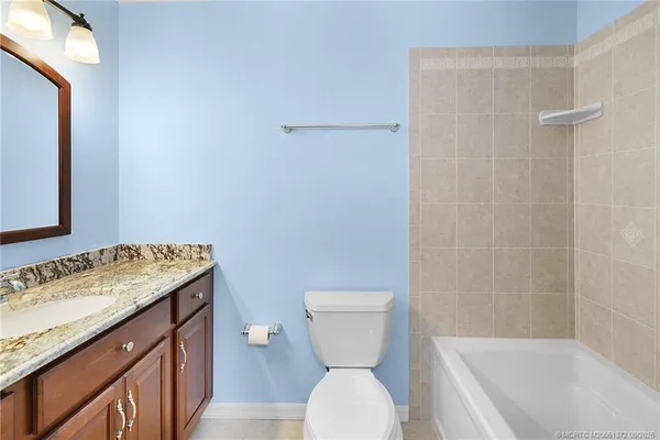 a bathroom with a granite countertop toilet a sink and a bathtub