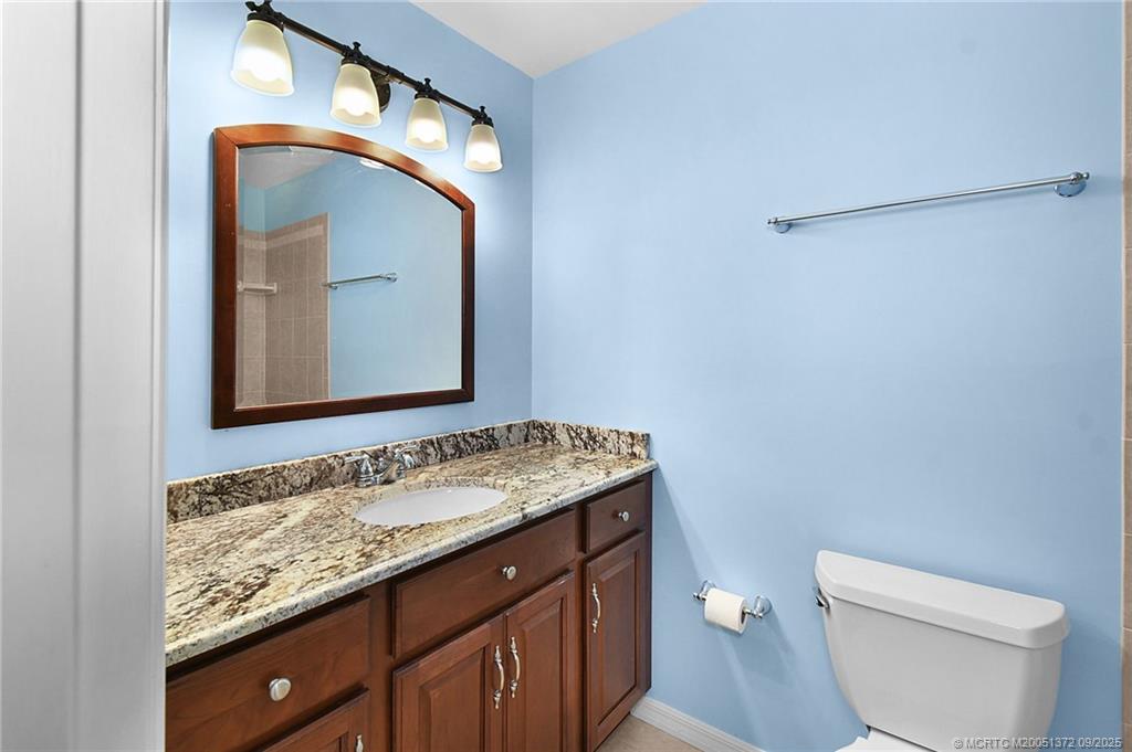 50 Southwest Blackburn Terrace, Unit 8 Stuart, FL 34997 - Photo 9 of 42 a bathroom with a granite countertop sink vanity mirror and toilet