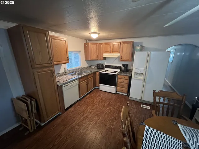 a kitchen with stainless steel appliances granite countertop a stove a sink dishwasher a refrigerator a sink dishwasher and a stove with wooden floor
