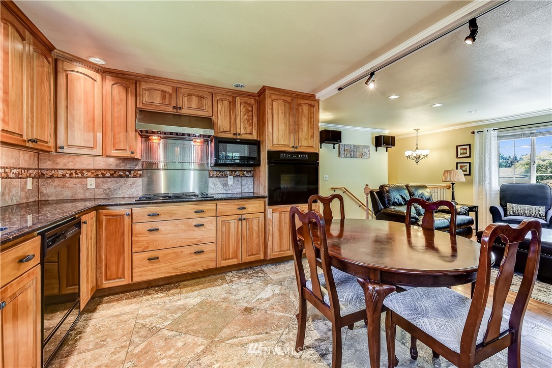417 212th Street Southwest Bothell, WA 98021 - Photo 10 of 28 a kitchen with stainless steel appliances granite countertop a table chairs and a refrigerator