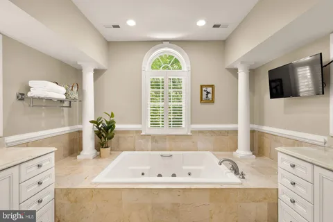 a bathroom with a tub a double vanity sink and a large mirror