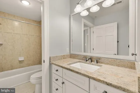 a bathroom with a granite countertop sink a toilet and bathtub