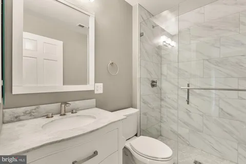 a bathroom with a granite countertop sink toilet a mirror and shower