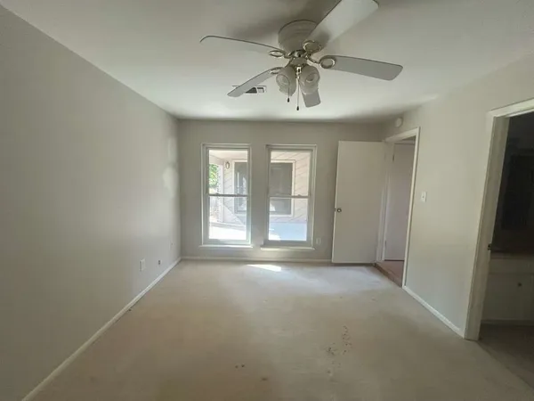an empty room with windows and chandelier fan