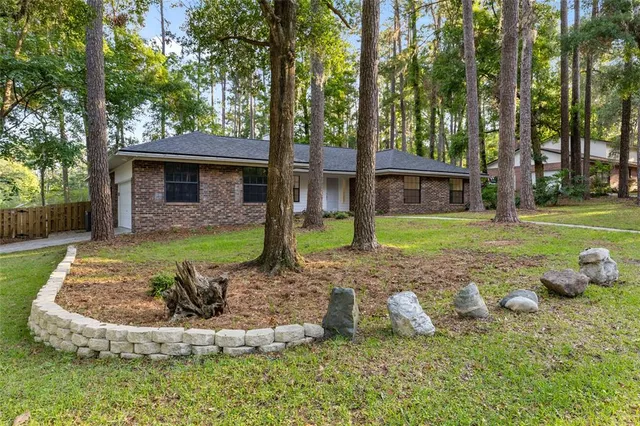 a view of a house with backyard and trees