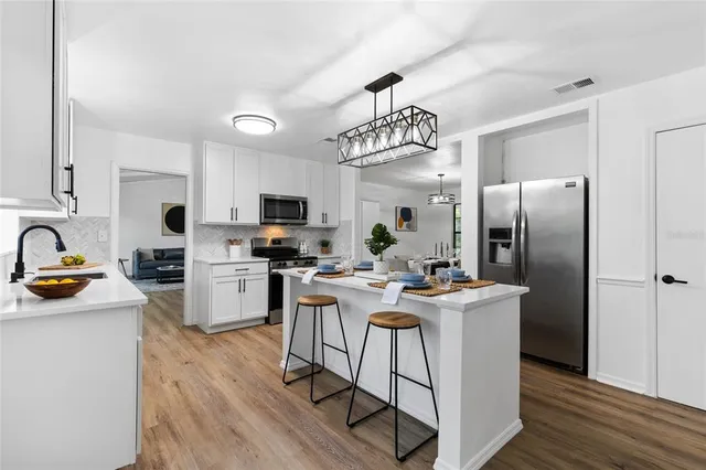 a view of a kitchen with kitchen island a counter top space a sink appliances and cabinets