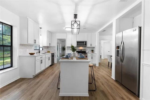 a kitchen with stainless steel appliances a refrigerator a sink dishwasher a stove and white countertops with wooden floor