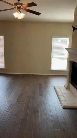 a view of a livingroom with wooden floor a ceiling fan and staircase