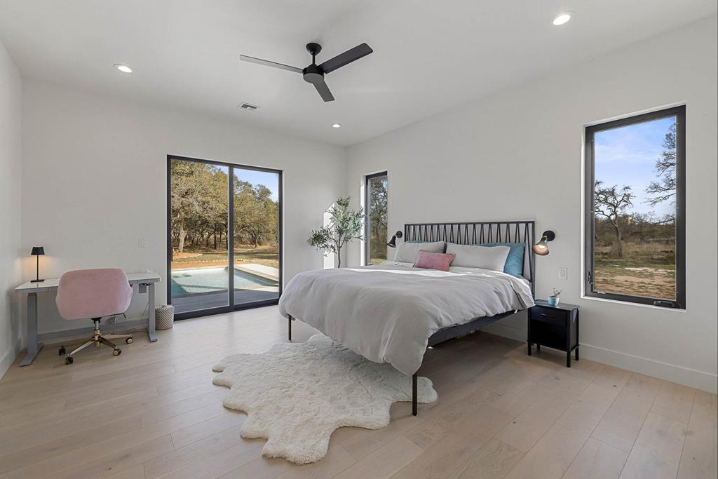 444 Klein Road Stonewall, TX 78671 - Photo 19 of 55 a bedroom with a bed a chair and painting on the wall