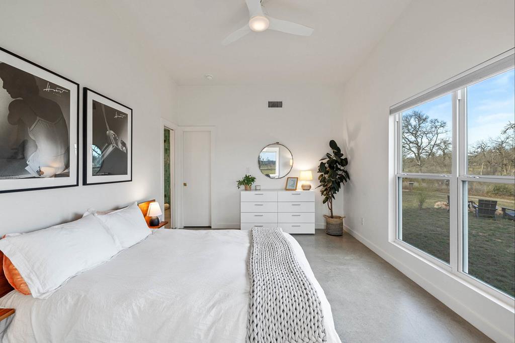 444 Klein Road Stonewall, TX 78671 - Photo 47 of 55 a bedroom with a balcony a bed and a painting on the wall