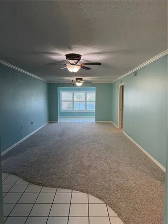 a view of an empty room with a chandelier fan and windows