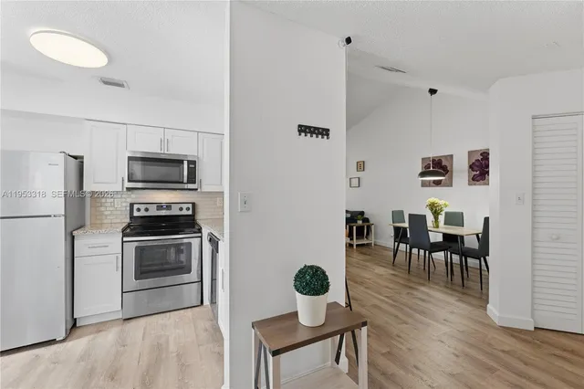 a kitchen with granite countertop stainless steel appliances a stove top oven a sink a dining table and chairs