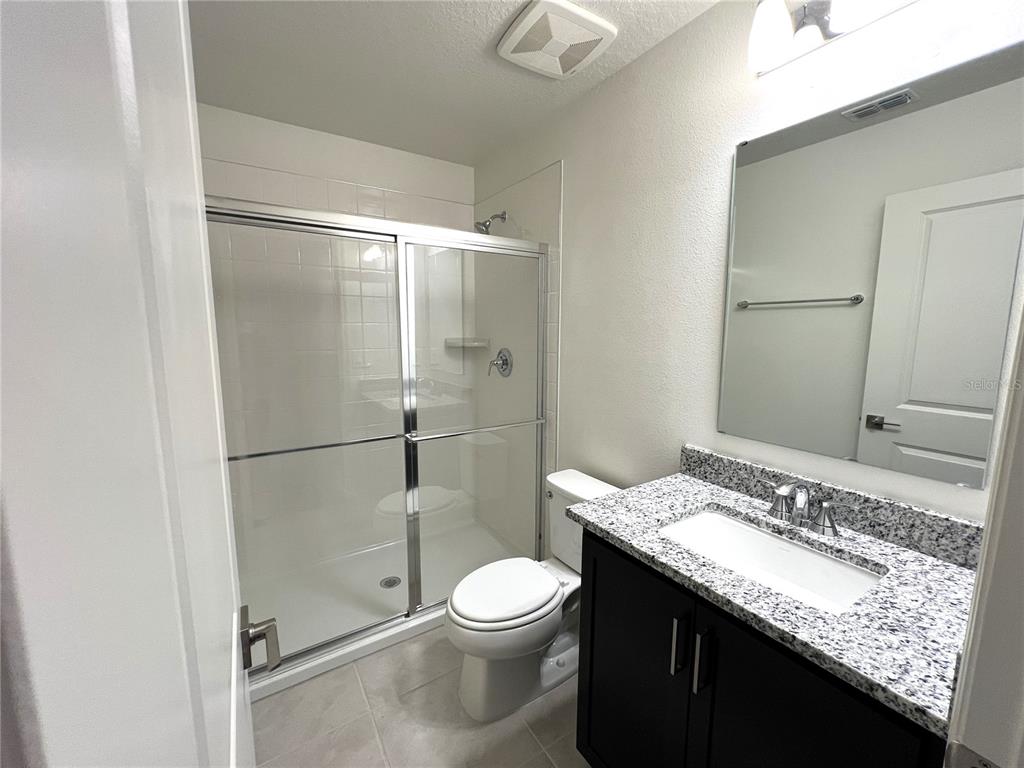 758 Stoney Point Circle Davenport, FL 33896 - Photo 32 of 42 a bathroom with a granite countertop sink toilet and shower