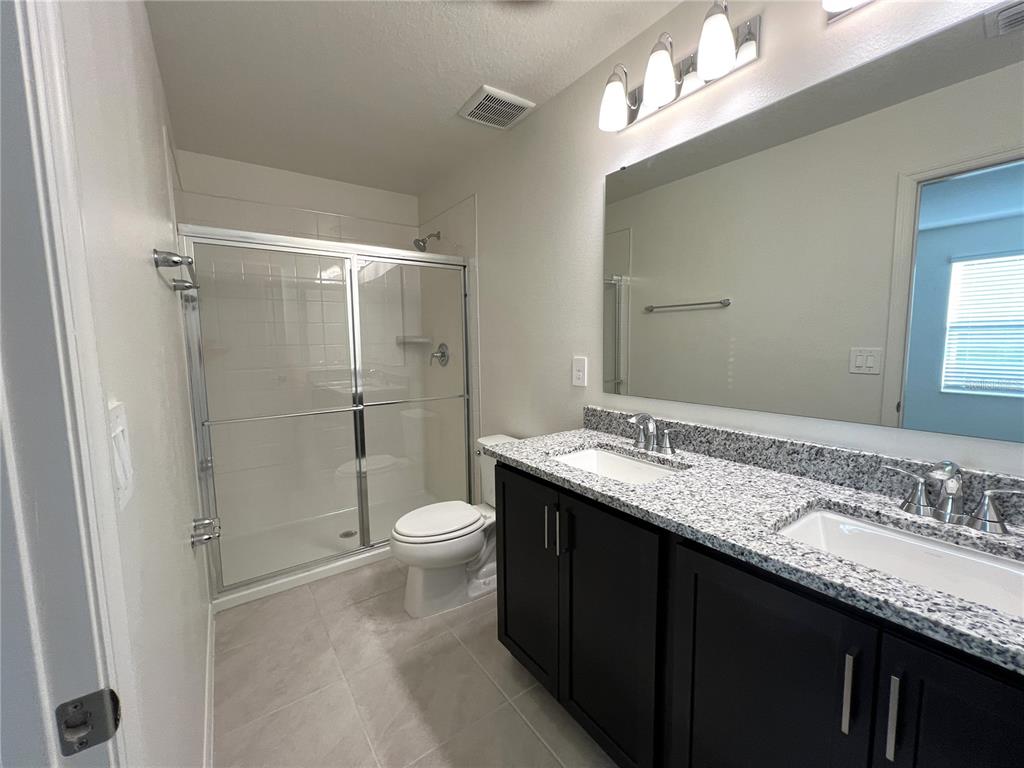 758 Stoney Point Circle Davenport, FL 33896 - Photo 38 of 42 a bathroom with a granite countertop sink toilet and shower