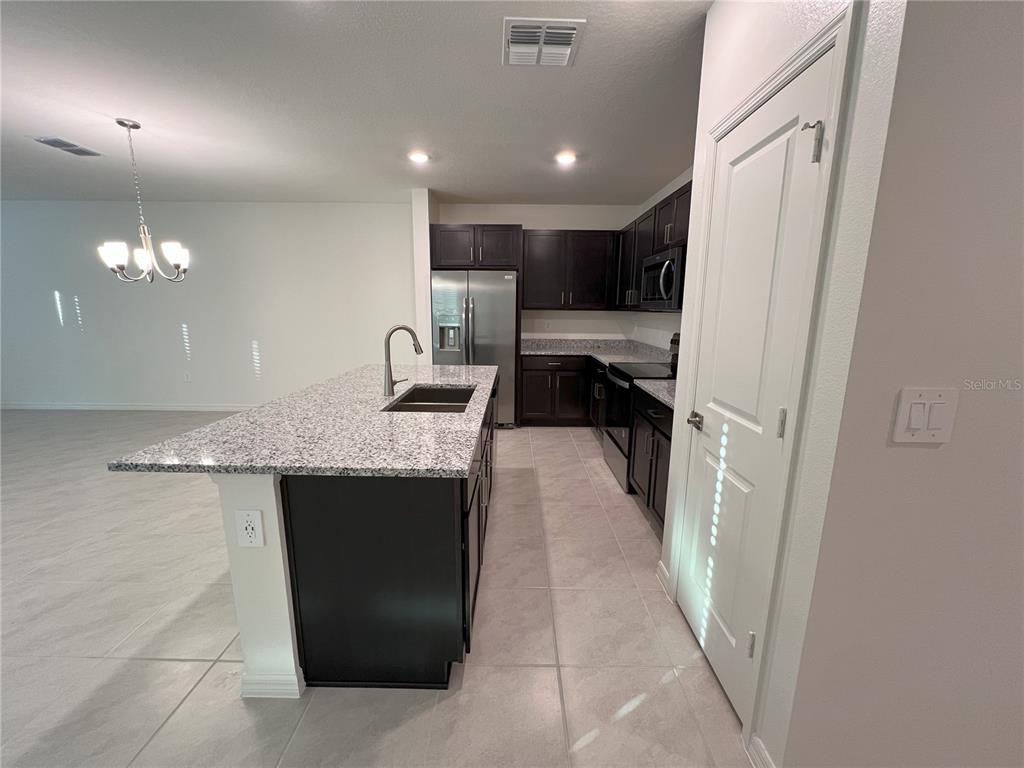 758 Stoney Point Circle Davenport, FL 33896 - Photo 5 of 42 a kitchen with kitchen island granite countertop a sink a counter top space and cabinets