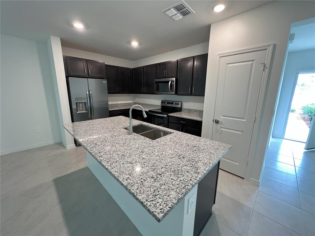 758 Stoney Point Circle Davenport, FL 33896 - Photo 7 of 42 a kitchen with stainless steel appliances granite countertop a sink refrigerator and microwave