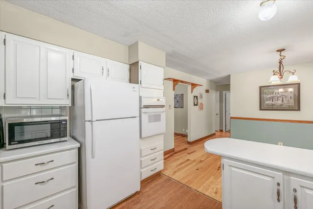 a white refrigerator freezer sitting in a kitchen with white cabinets