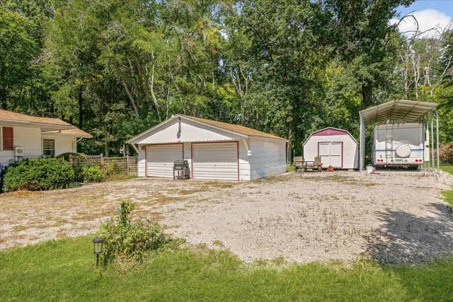a front view of a house with a yard and large tree