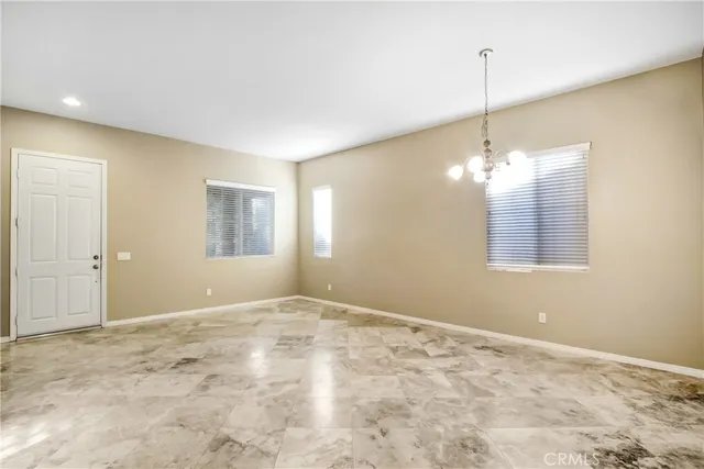 a view of an empty room with window and chandelier fan