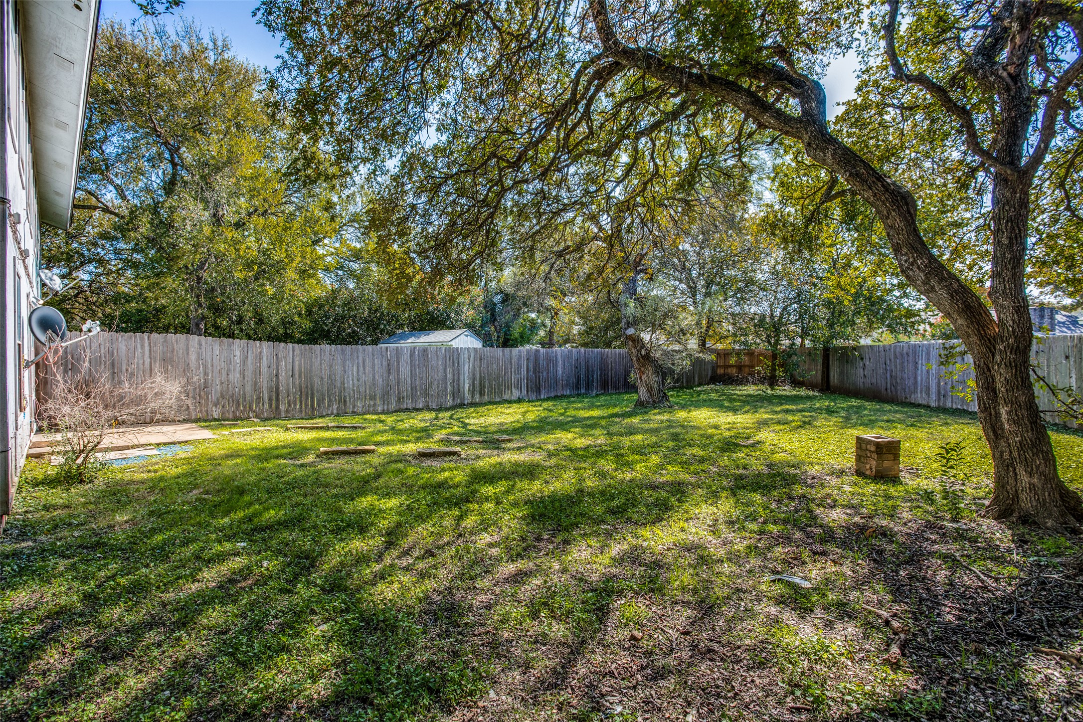 106 Verna Spur, Unit B Georgetown, TX 78628 - Photo 25 of 25 A fenced backyard offers a verdant lawn and mature shade trees, providing ample space for outdoor enjoyment.