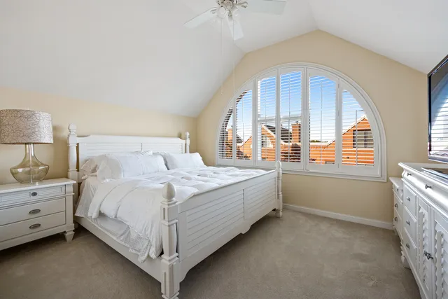 a spacious bedroom with a bed a mirror and windows