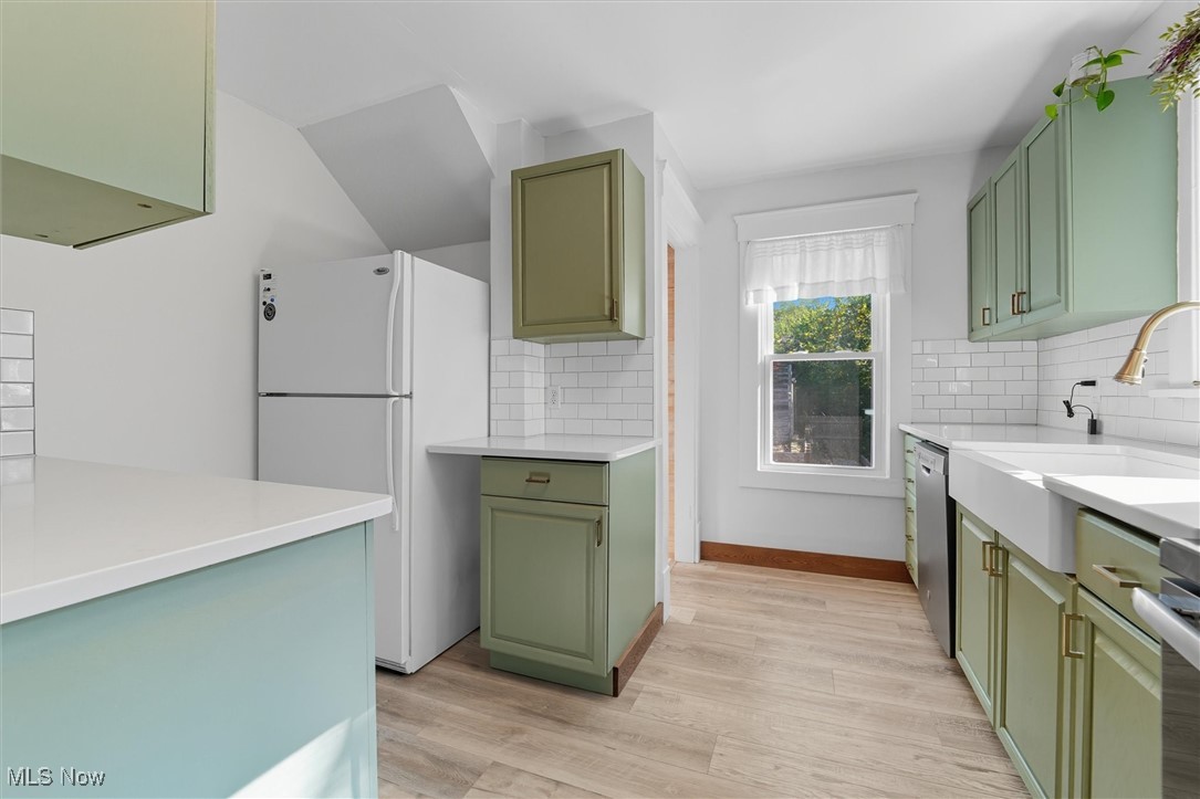 10536 Johnnycake Ridge Road Painesville, OH 44077 - Photo 10 of 40 Kitchen with green cabinetry, stainless steel appliances, light wood-style flooring, and decorative backsplash