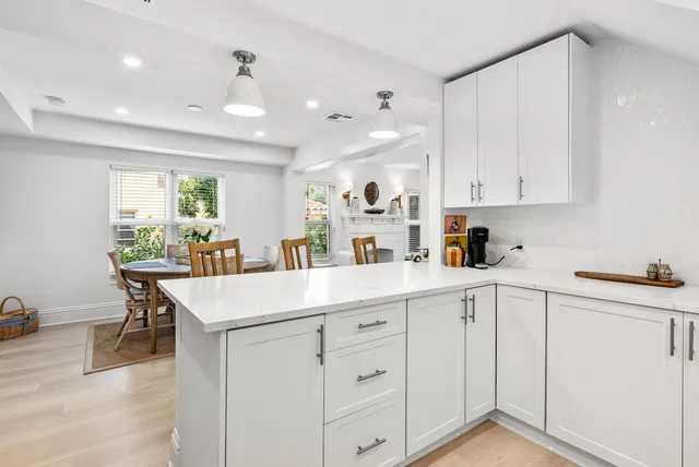 a kitchen with white cabinets sink and chairs