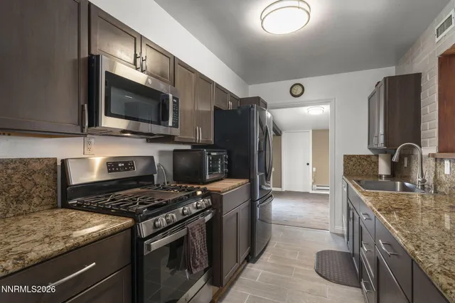 a kitchen with stainless steel appliances granite countertop a sink stove microwave and refrigerator