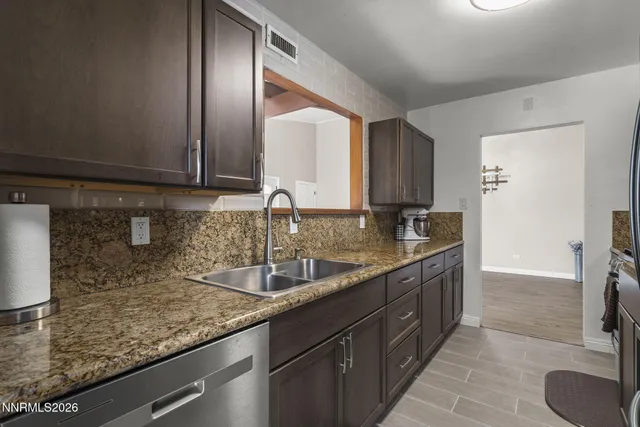 a kitchen with granite countertop a sink a stove and cabinets