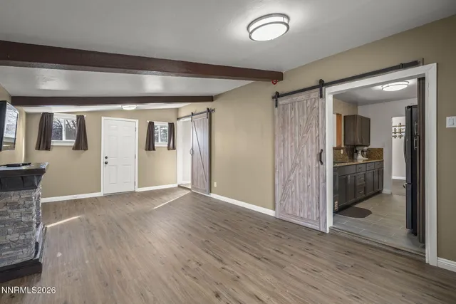 a view of a hallway with wooden floor and a kitchen