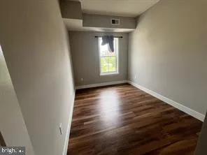 a view of an empty room with wooden floor and a window