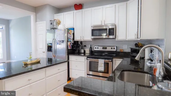 a kitchen with stainless steel appliances granite countertop a sink a stove and refrigerator