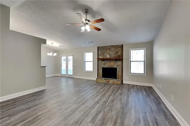 an empty room with wooden floor fireplace and a window