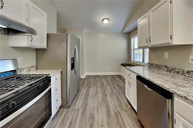 a kitchen with granite countertop a sink stove and cabinets