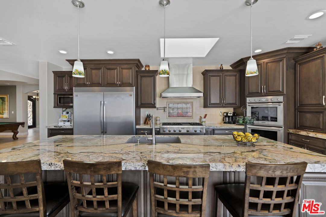 5437 Middlecrest Road Rancho Palos Verdes, CA 90275 - Photo 4 of 32 a kitchen with stainless steel appliances kitchen island granite countertop a table chairs sink and cabinets